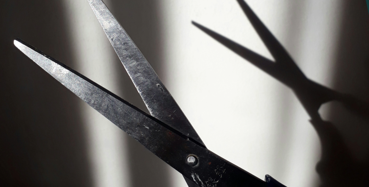 Schere im Vordergrund, die einen Schatten wirft in Schwarz-Weiß
